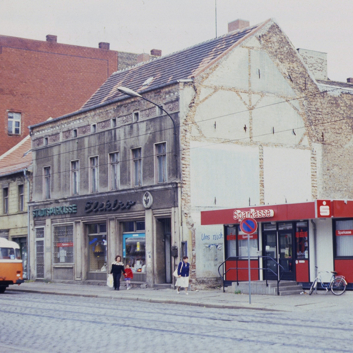 An die Stellen eines abgerissenen Hauses, das nicht zu retten war, kommt eine Sparkasse. Der Geldfluss muss her Anfang der 90er. Die Sanierung kommt später.