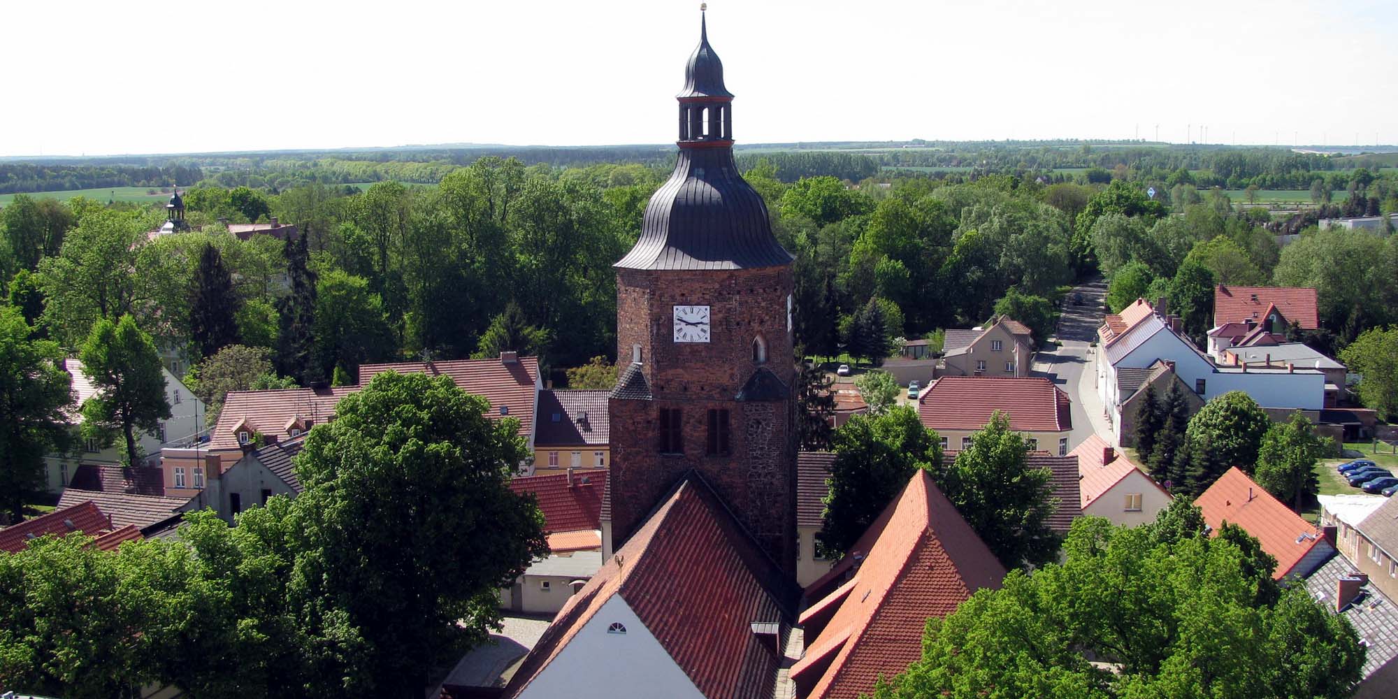 Die Kirchenschiffe im Vordergrund und der Turm, im Hintergrund die grüne Umgebung