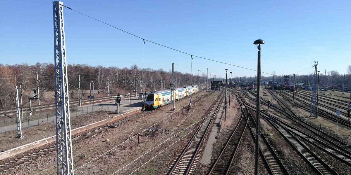 Ein Zug der im Bahnhof hält und im Hintergrund ist eine Bahnanlage