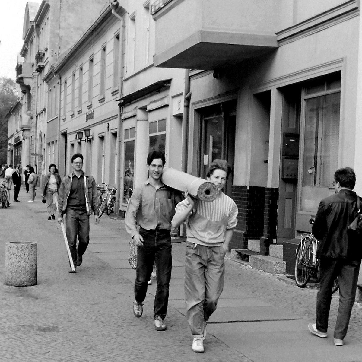 Zwei junge Männer tragen Anfang der 90er Jahre einen Teppich durch die Stadt im Aufbruch
