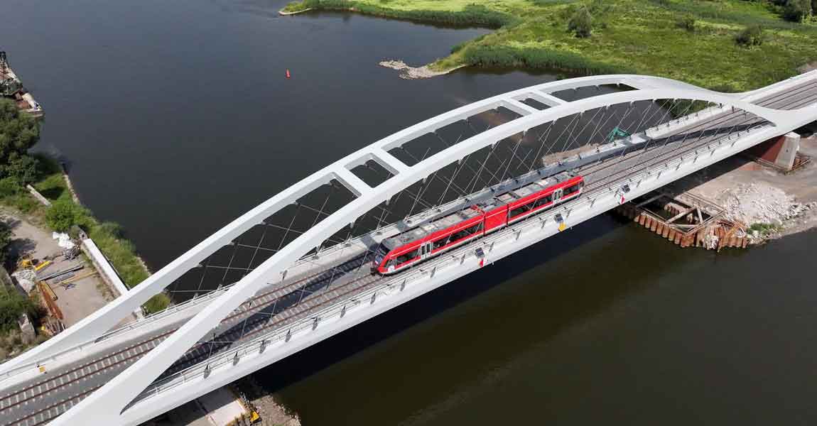 eine Eisenbahnbrücke in besonderer Bauweise mit einem roten Zug 