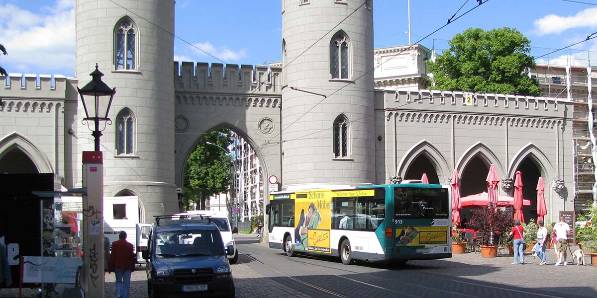 Reger Verkehrsfluss in der Innenstadt durch ein historisches Tor hindurch