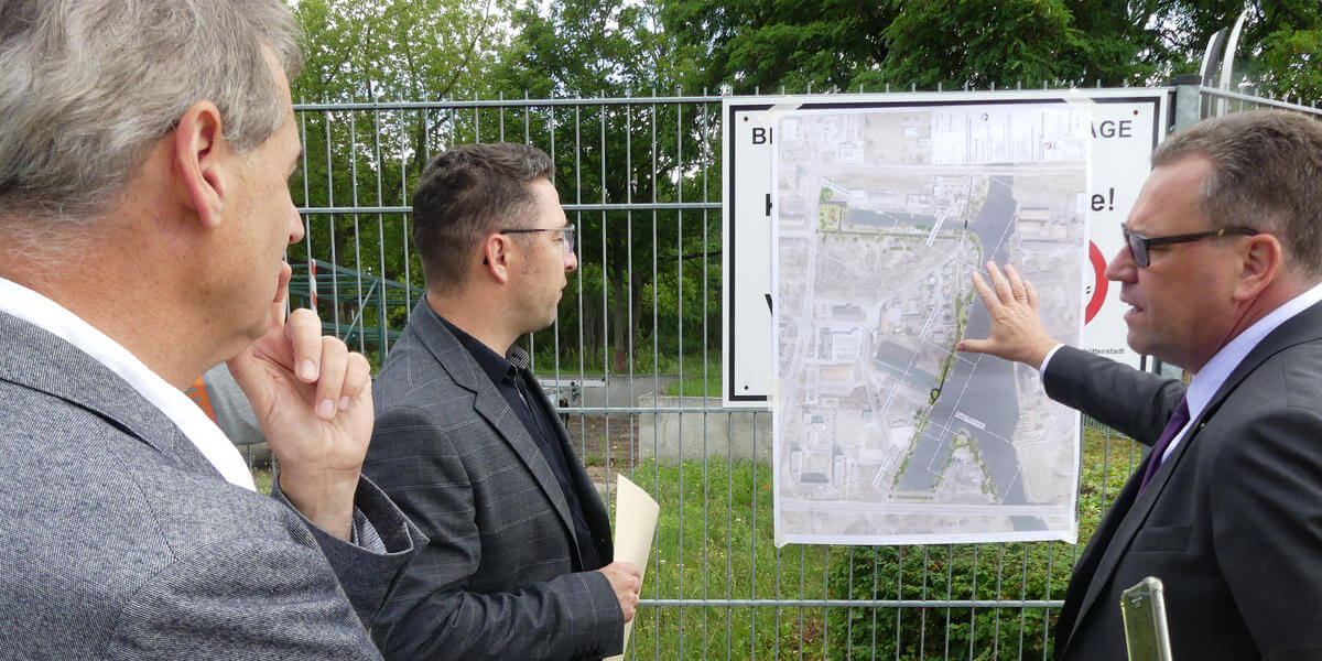 Staatssekretär Rainer Genilke schaut auf einen Plan zu Neugestealltung der Uferzone