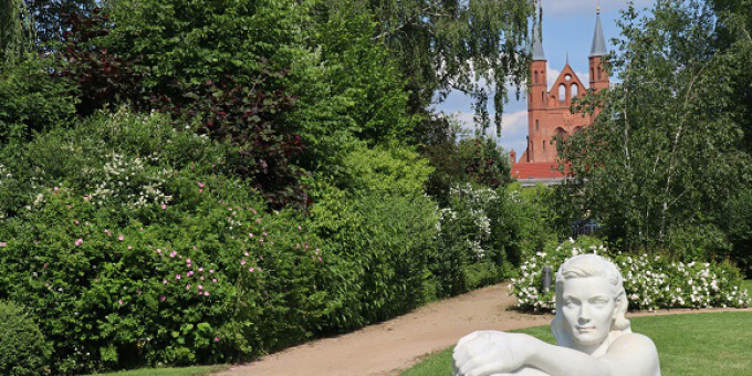 Blick durch den Rosengarten, eine Skulptur im Vordergrund