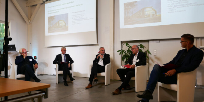 Auf der Bühne findet eine Podiumsdiskussion statt
