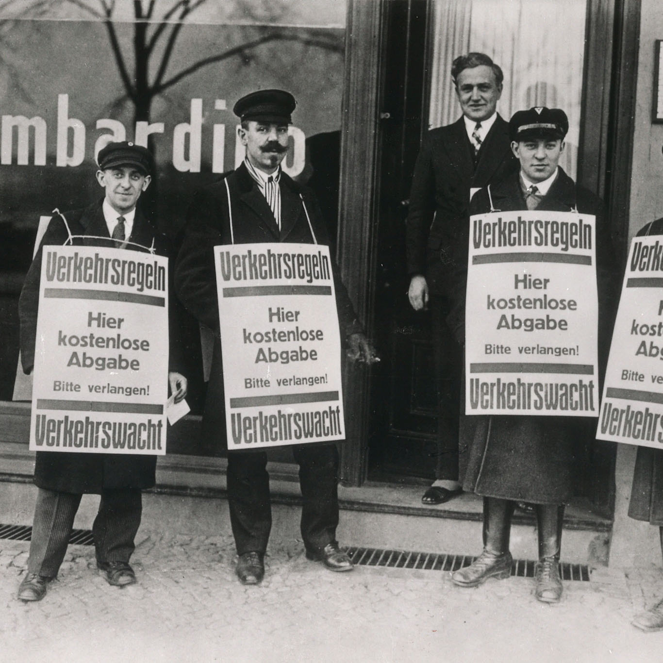 Foto von früher: Männer in Kleidung der 20er Jahre machen eine Plakataktion für mehr Verkehrssicherheit